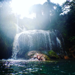 Girl under a waterfall in a natural pool at El Nicho Cuba
