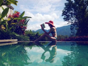Sofie reading by the pool with a view
