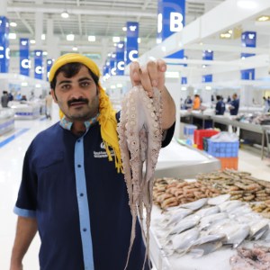 Fishmonger with octopus, new Deira fish souk Dubai